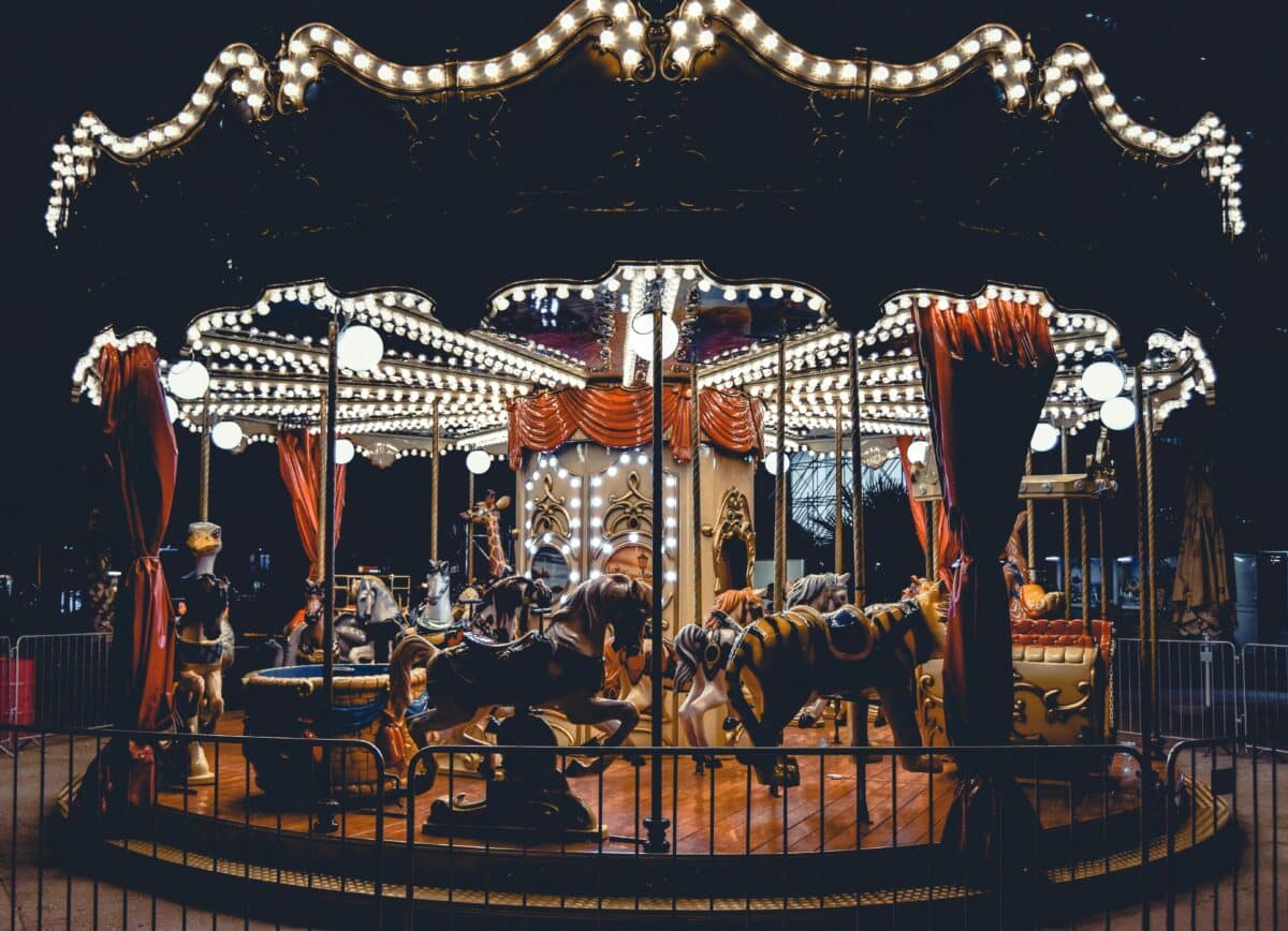 A beautifully illuminated carousel spins in Bucharest's night scene, capturing the whimsical charm of a classic fairground ride.